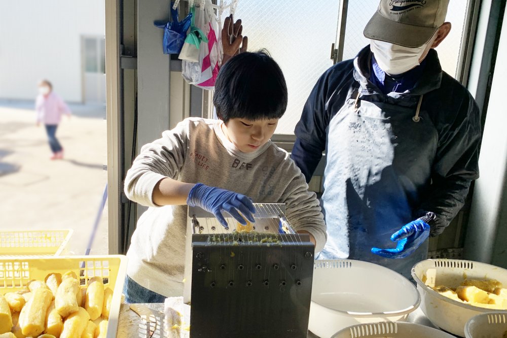 ほしいも作りのなかでも最も難しいと言われるカット作業。熱々の芋を“つき台”と呼ばれるピアノ線を張った台に通してカットしていく。